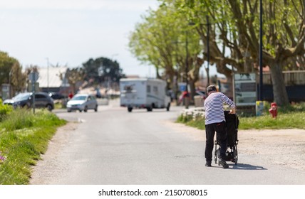 An Elderly Man Pushing A Stroller