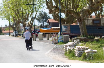 An Elderly Man Pushing A Stroller