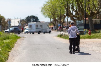 An Elderly Man Pushing A Stroller