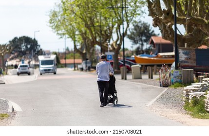 An Elderly Man Pushing A Stroller