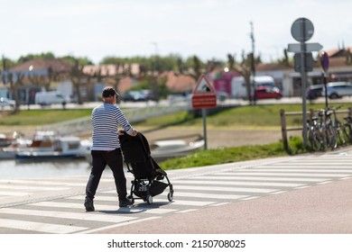 An Elderly Man Pushing A Stroller