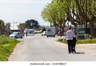 An Elderly Man Pushing A Stroller