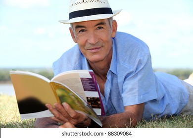 Elderly Man Reading A Book Outside