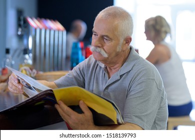 Elderly Man Reading Magazine In The Cafe