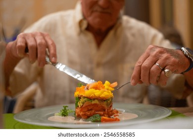 Elderly man at restaurant eats healthy gourmet salad plate consisting of fruit, vegetables and salmon, papaya, avocado, mango - Powered by Shutterstock