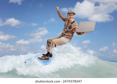 Elderly man riding a surfboard on a wave in the sea and holding a laptop computer  - Powered by Shutterstock