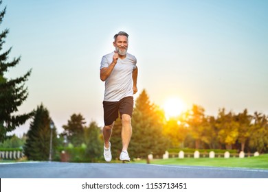 The elderly man running on the road on the sunrise background - Powered by Shutterstock