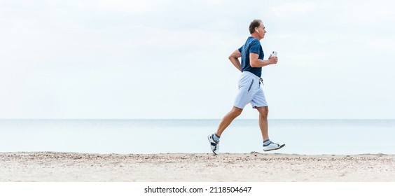 Elderly man runs early morning by sea beach. Active senior man is jogging. Healthy retirement lifestyle. - Powered by Shutterstock