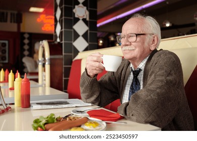 Elderly man savoring cup of coffee while seated in retro diner, showcasing a nostalgic ambiance with classic decor, surrounded by breakfast items and reading material - Powered by Shutterstock