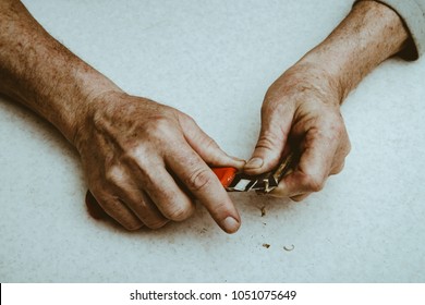 Elderly man sharpens pencil with clerical knife. Hands of old man close up. - Powered by Shutterstock