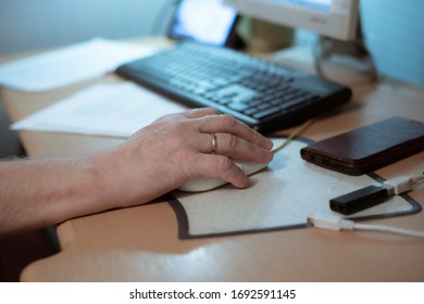 An Elderly Man Sits At A Table And Works On A Computer, Holds A Computer Mouse With His Hand, Socialization Of People Of Retirement Age