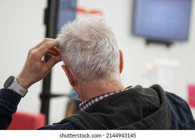 An elderly man sits thoughtfully indoors. Station, airport or government agency. Social assistance, support for the elderly or parents. No face. Close-up - Powered by Shutterstock