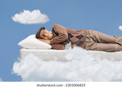 Elderly man sleeping on a matress and floating on clouds - Powered by Shutterstock