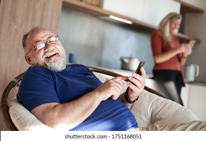 elderly man with a smartphone sitting in a home chair. - Shutterstock ID 1751168051