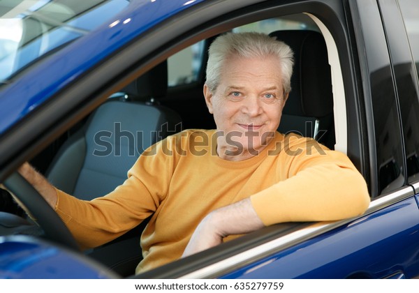 Elderly man smiling happily sitting in his car\
comfort luxury travelling safety insurance pensioner retired\
retiring seniority lifestyle transportation automotive sales offer\
driving driver owning