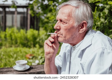 Elderly man smoking a cigarette, wearing a white shirt, outdoors. Reflective, personal moment, suitable for health or lifestyle content. - Powered by Shutterstock