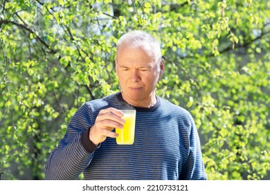 An Elderly Man With A Soluble Fizzy Vitamin Drink Against The Background Of Spring Foliage