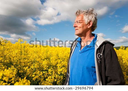elderly man standing in coleseed fields