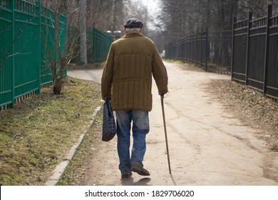 An elderly man with a stick is walking down the street. A man aged. The old grandfather is walking. The life of pensioners in Russia. Old age in the fall.