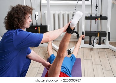 Elderly Man Stretching Rehab Physio Band With Young Physiotherapist