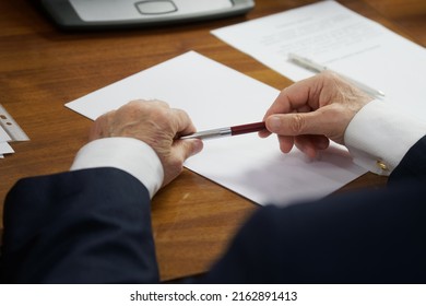 Elderly Man In A Strict Business Suit, Sitting At A Table With A Fountain Pen, Thinks About Filling Out Documents, Form Or Will. The Concept Of Writing A Will Or Filling Out Forms. No Face