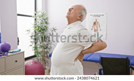 Elderly man suffering from excruciating back pain undergoes physiotherapy at rehab clinic