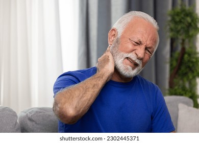 Elderly man suffering from neck pain sitting on sofa at home - Powered by Shutterstock