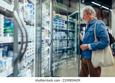 Elderly Man Supermarket Grocery Shopper Looking At Refrigerated Searching For Milk Product