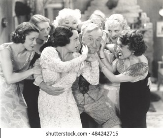 Elderly man surrounded by flirtatous young women