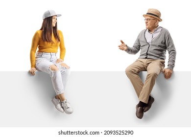 Elderly Man Talking To A Female Teenager And Sitting On A Blank Panel Isolated On White Background