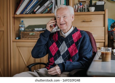 Elderly Man Talking On Phone Sitting At Home