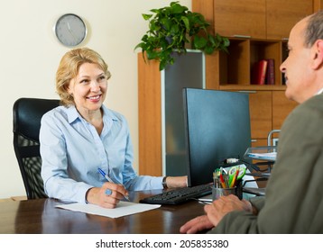 Elderly Man Talking With Smiling Female Bank Manager About Opening Saving Account