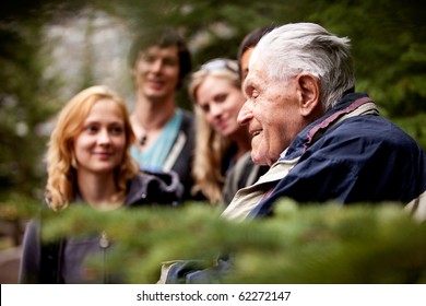 An elderly man telling stories to a group of young people