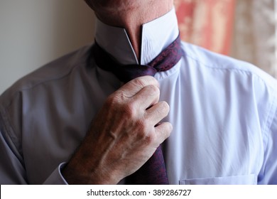 An elderly man ties a tie around his neck. The old man dressed for the meeting. The dress code for men. - Powered by Shutterstock