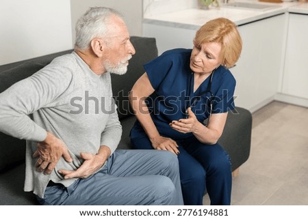 Elderly man touch lower back complaint to pain, muscle spasm, tightness in pelvis, sharp ache kidneys infection to nurse. A doctor talks to an patient during a home visit.