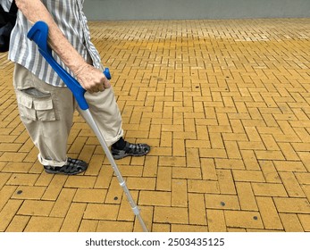 elderly man using crutches walking down the street - Powered by Shutterstock