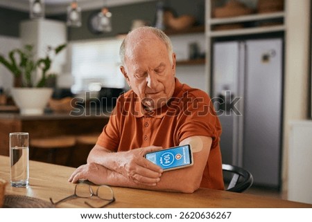 Elderly man using digital sensor to measure blood sugar levels at home. Senior monitoring glucose levels with a digital medical sensor device. Old man with diabetes monitoring blood sugar level.