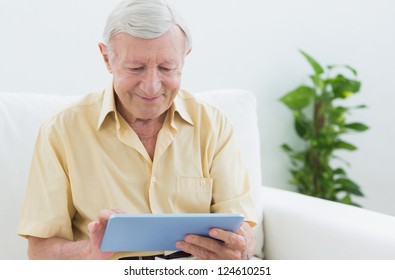 Elderly Man Using A Digital Tablet On A Sofa