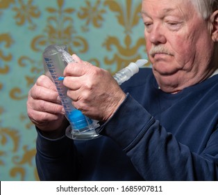 Elderly Man Using Incentive Spirometer For Breath Improvement.  Helpful For Pneumonia Or A Lung Condition Like Chronic Obstructive Pulmonary Disease (COPD) Or Cystic Fibrosis. 