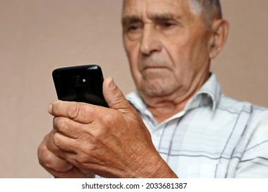 Elderly man using mobile phone, looking on smartphone screen. Concept of online communication in retirement, sms, reading news