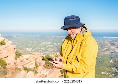 Elderly Man Using Phone To Check Map During Hiking Trip