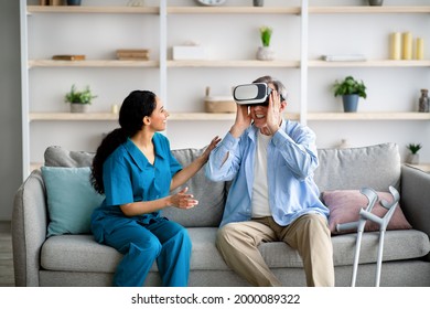 Elderly man using VR headset with young medical worker, exploring augmented reality at retirement home. Senior male patient with caregiver learning to play virtual game, having fun - Powered by Shutterstock