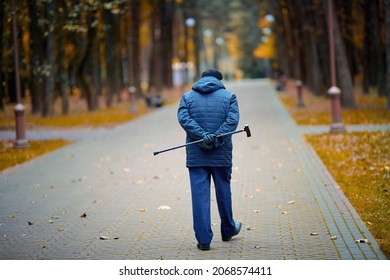 Elderly man walking with walking cane in hand behind his back. Old man with cane enjoying walk in autumn city park. Senior man walk alone. - Shutterstock ID 2068574411