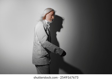 Elderly man walking in elegant attire against a gradient background, demonstrating a sense of calm and introspection, with soft shadows highlighting his movement and expression - Powered by Shutterstock