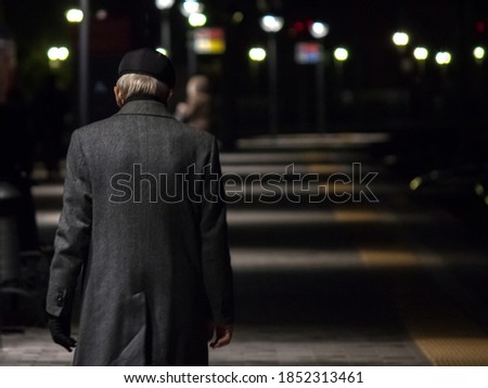 An elderly man walks in the late evening on a railway platform in St. Petersburg on his train home