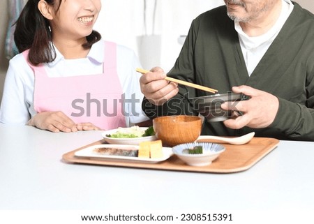 An elderly man who eats and a female caregiver in an apron
 Foto stock © 