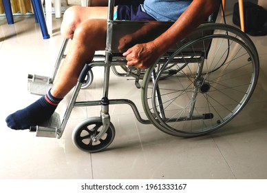 An elderly man who had a leg amputated under his left knee. Sitting on a wheelchair and using his hands to turn the wheel manually to move around the point of need.