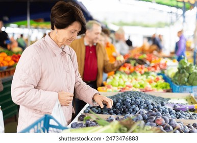 Elderly man and woman buying plums at - Powered by Shutterstock