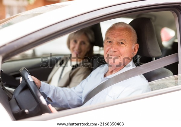 Elderly man and woman driving a car in the city. Man\
driving a car