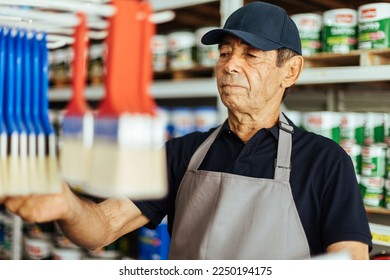 Elderly man working in a hardware store restocking items on shelves. Small business concept. - Powered by Shutterstock